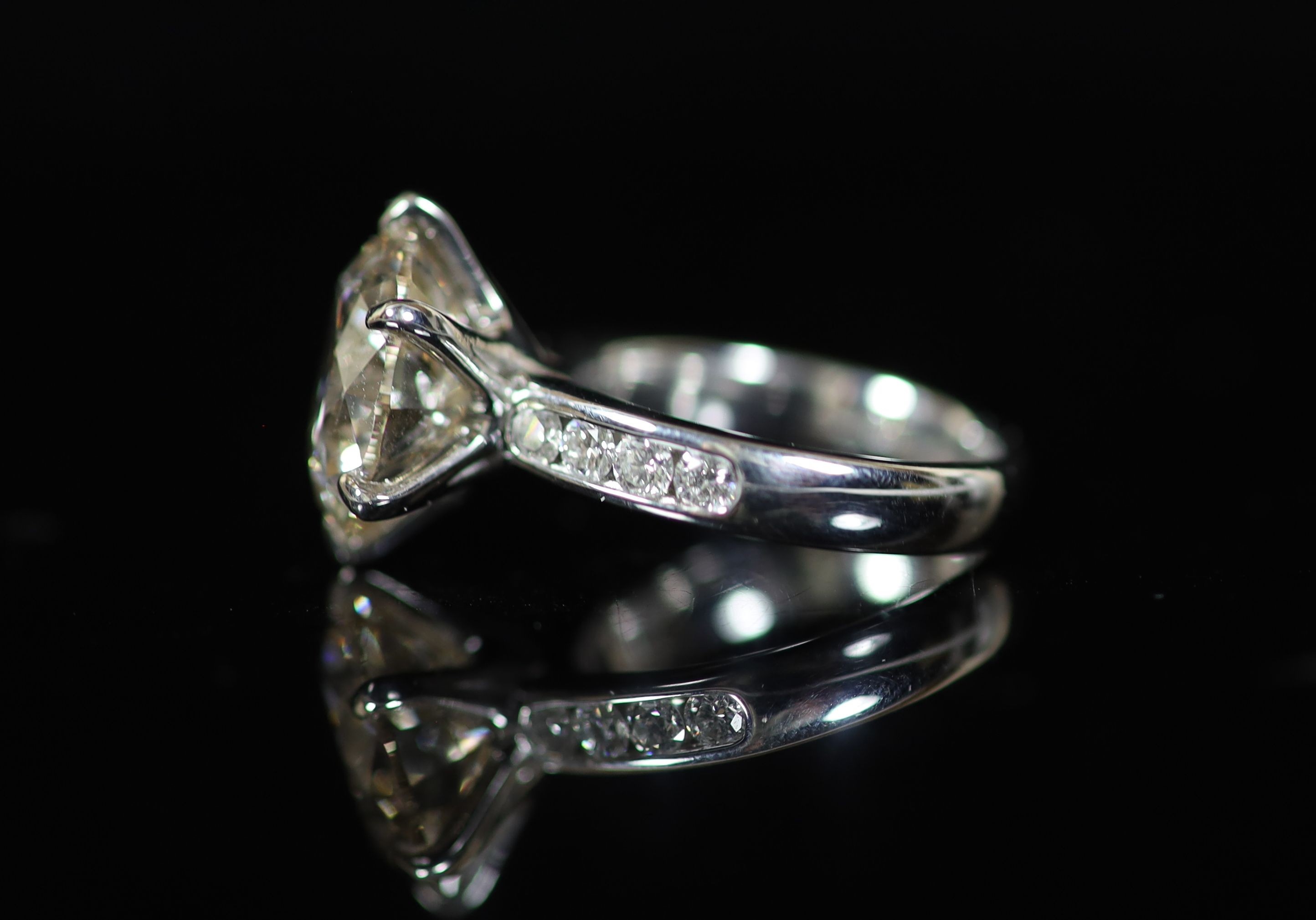 A modern platinum and single stone diamond ring, with diamond set shoulders, with AGI Laboratories report dated 23/5/2016, stating the round brilliant cut stone to weigh 7.77cts